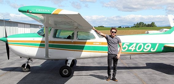 Male student standing next to small plane