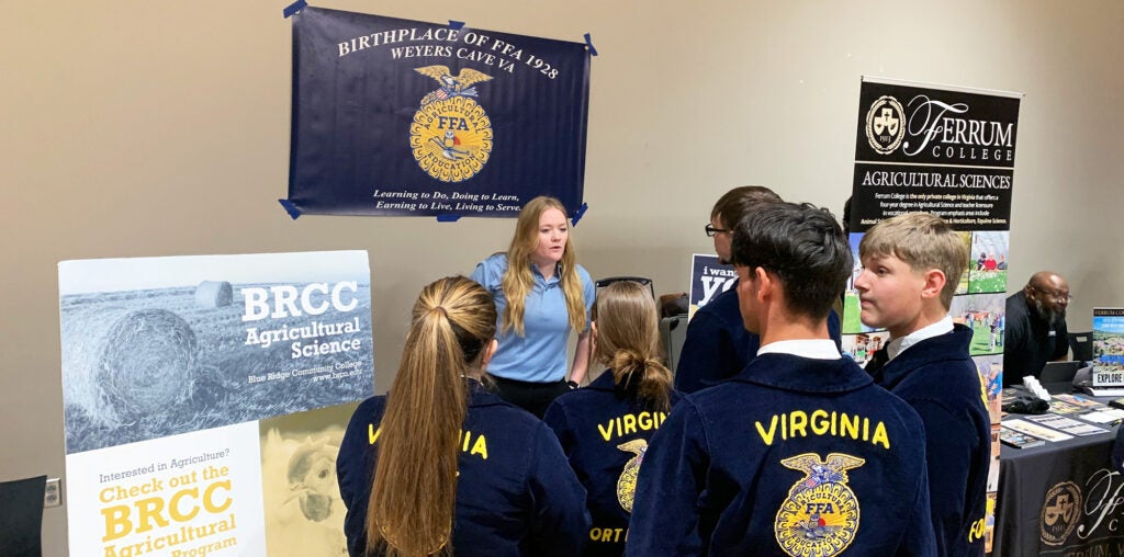 BRCC Agricultural program display at an expo table, with local high school students talking to a woman behind the table