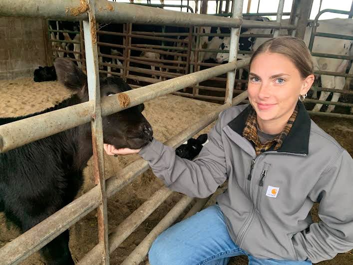 Student in BRCC barn with a black goat