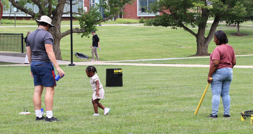 A family playing a game on the lawn of the quad
