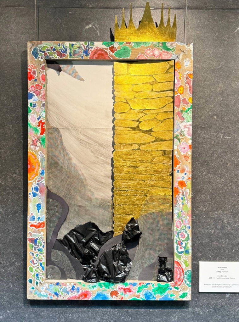 Art piece with decorated frame surrounding tan, gold, and lumpy black