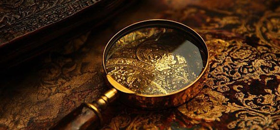Brass magnifying glass on gold and burgundy cloth