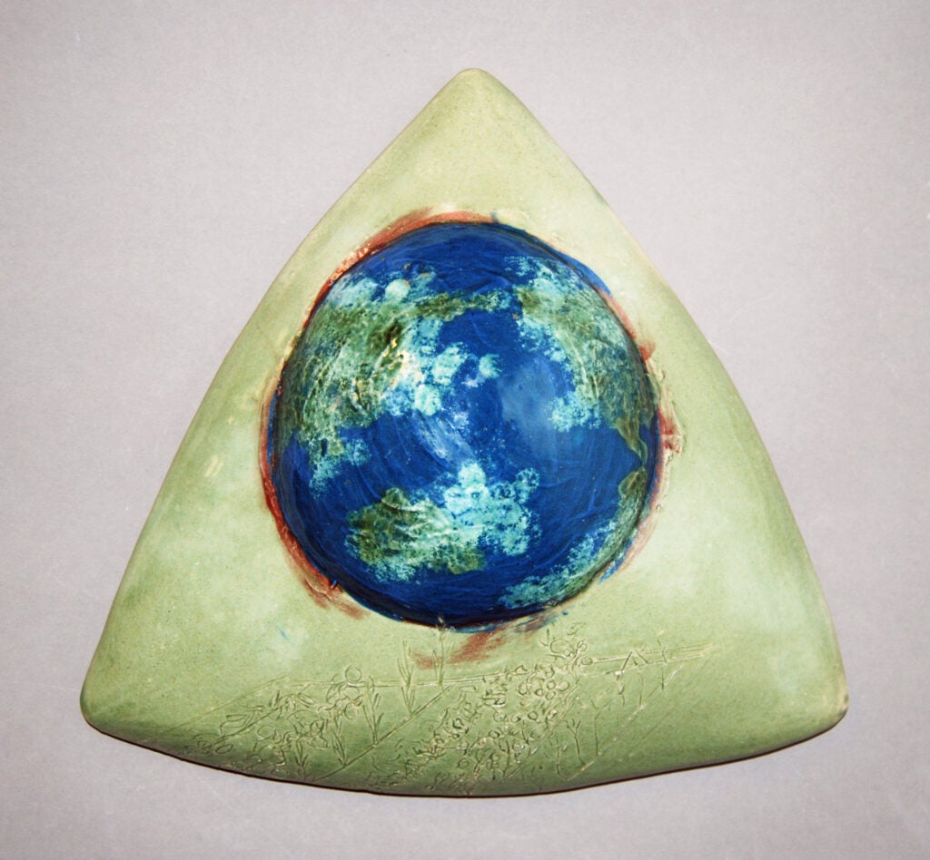 Ceramic sculpture of triangle shape with foliage pattern and a hemisphere of globe, entitled "Victory Garden" 2019 by Jessica Martinkosky