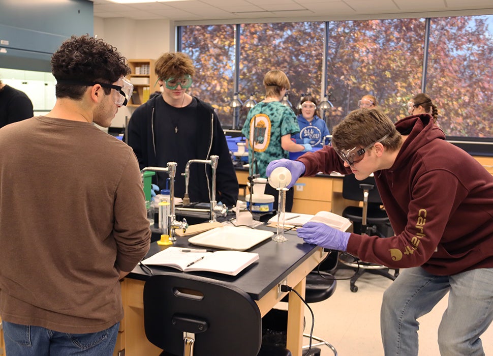 Chemistry lab action scene with student pouring liquid into a tall beaker